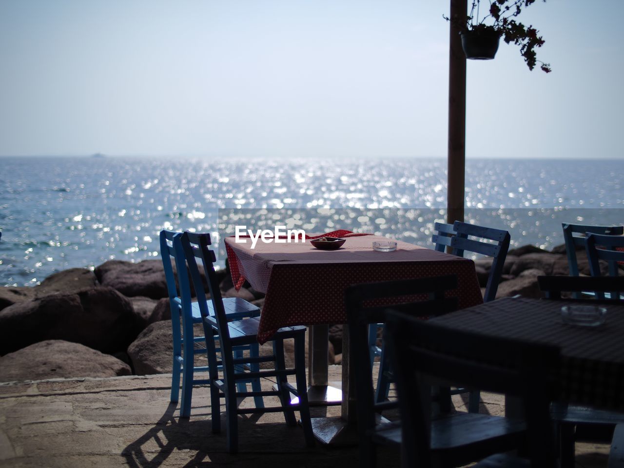 Empty chairs and table at restaurant against horizon