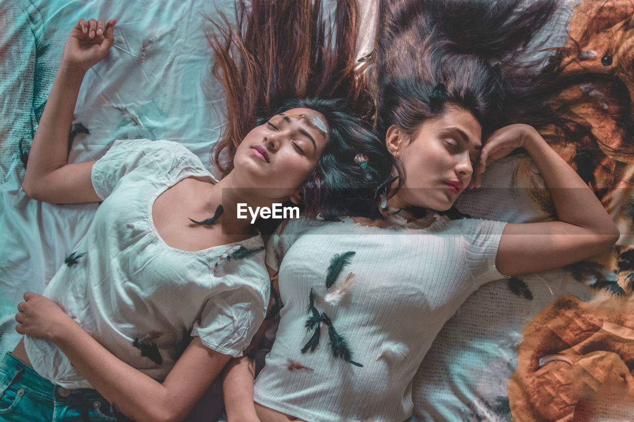 High angle view of friends sleeping on bed at home