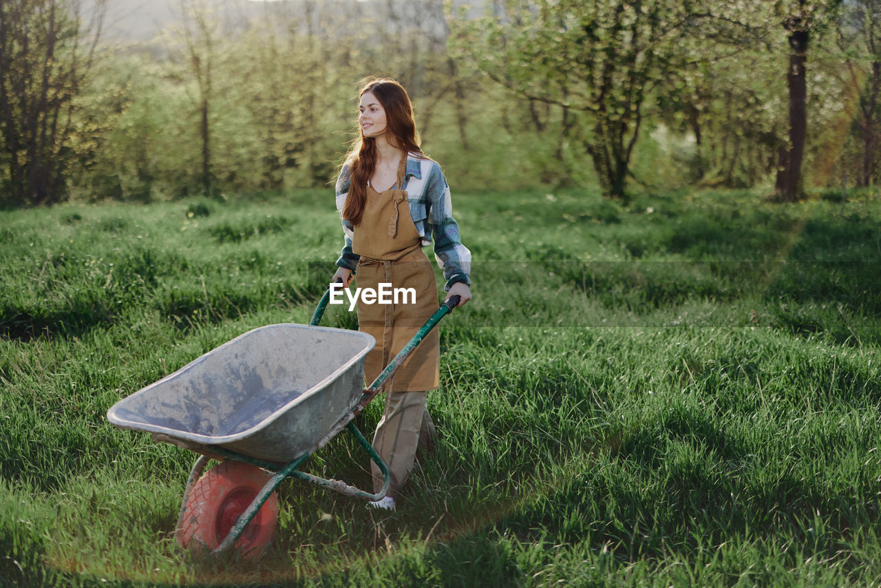 Young farmer with wheelbarrow walking n farm