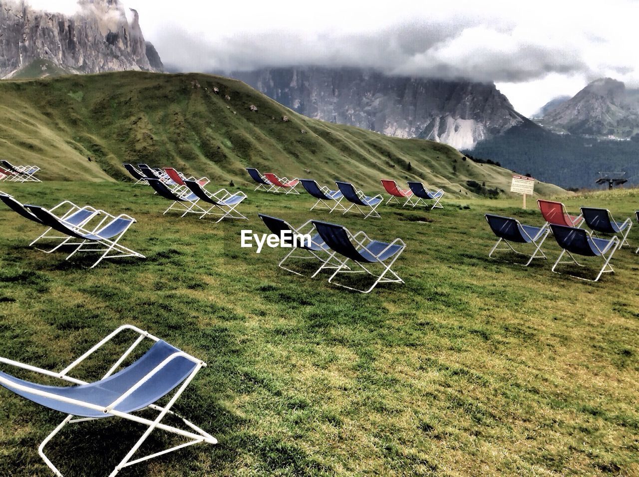 Empty foldable chairs on grassy field