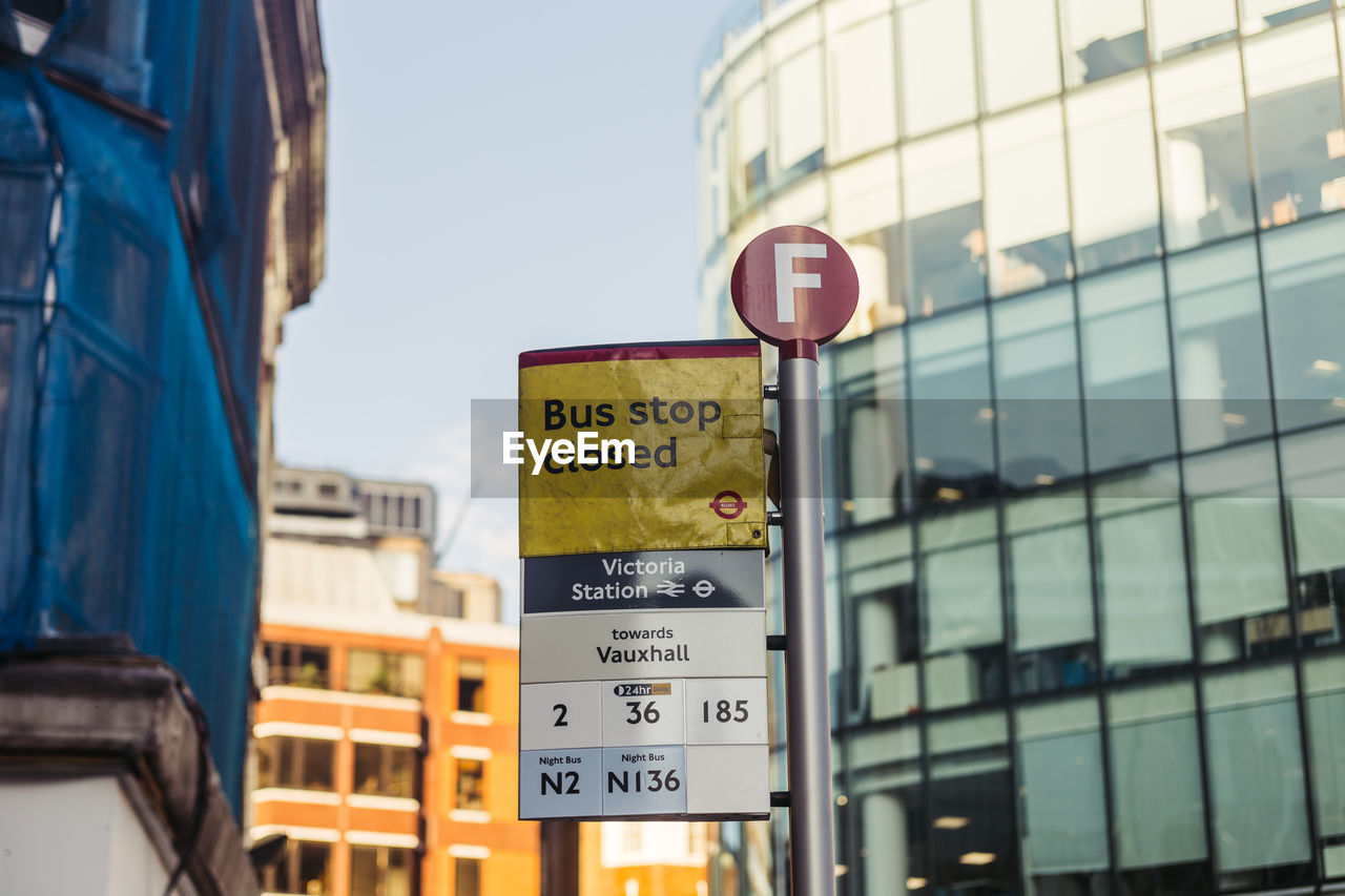 Low angle view of road sign by building in city