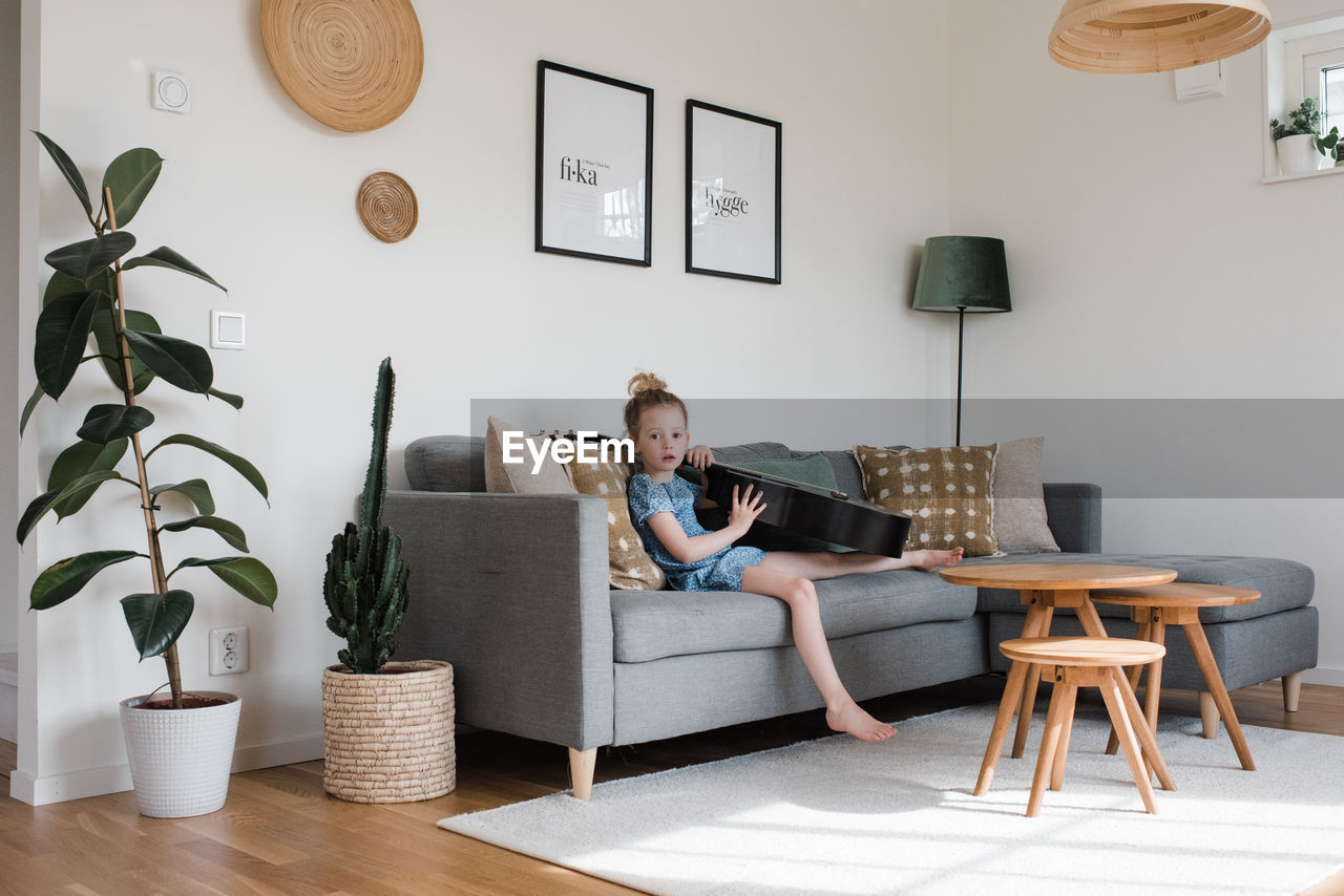 Young girl sat with a musical instrument, guitar at home