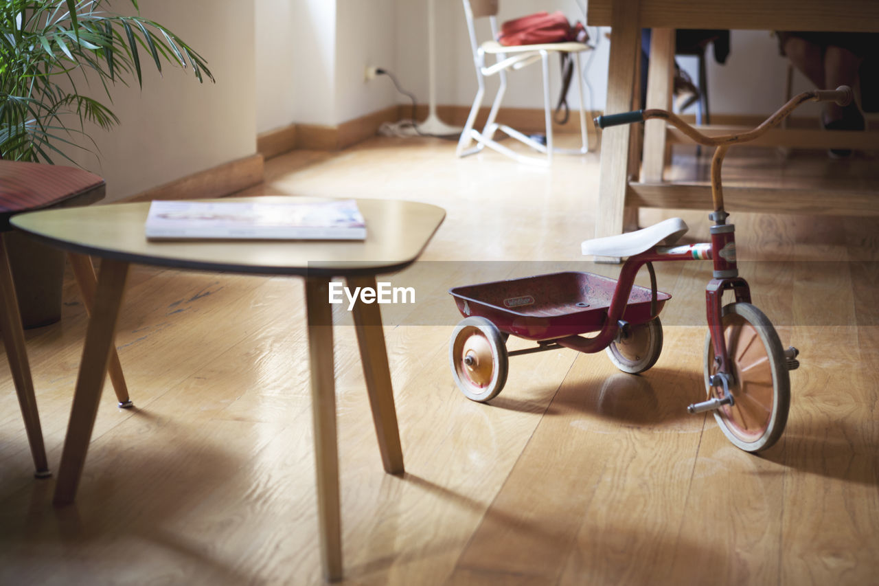 High angle view table and tricycle on hardwood floor at home