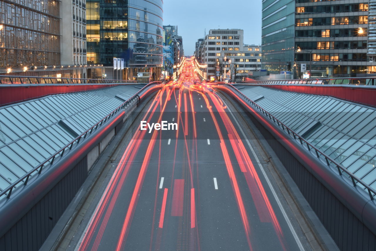 Light trails on road amidst buildings in city at night