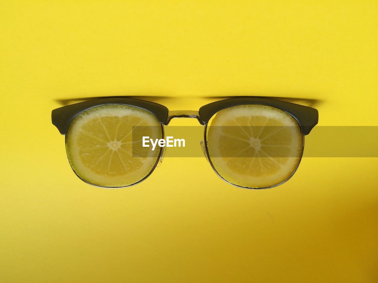 Eyeglasses made by lemon slices against yellow background