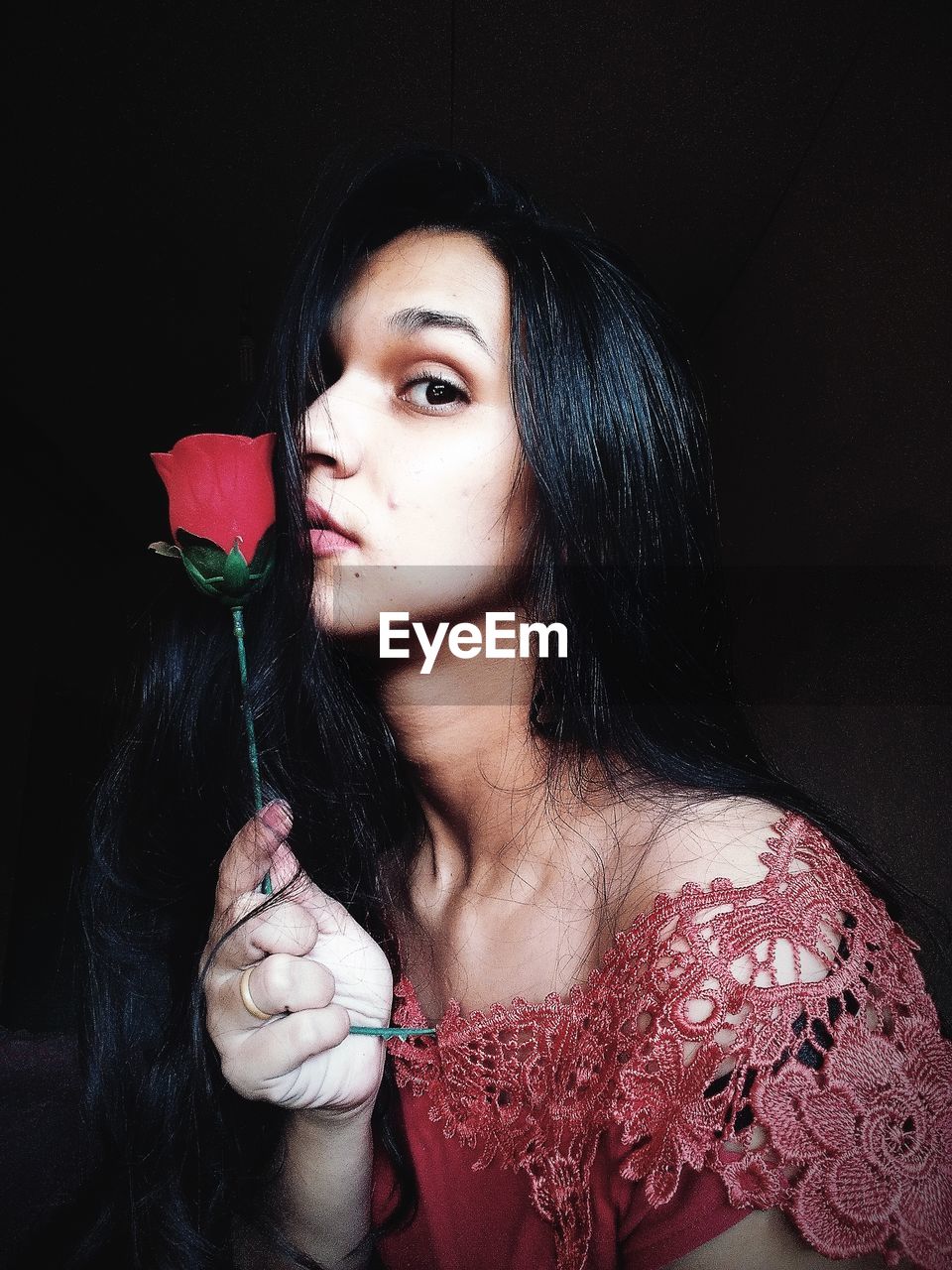 PORTRAIT OF WOMAN HOLDING FLOWERS IN BLACK BACKGROUND