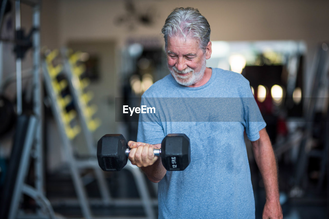 Smiling senior man exercising in gym