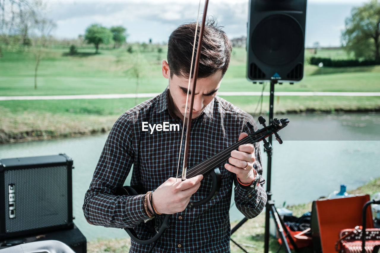 YOUNG MAN HOLDING CAMERA WHILE SITTING ON STAGE