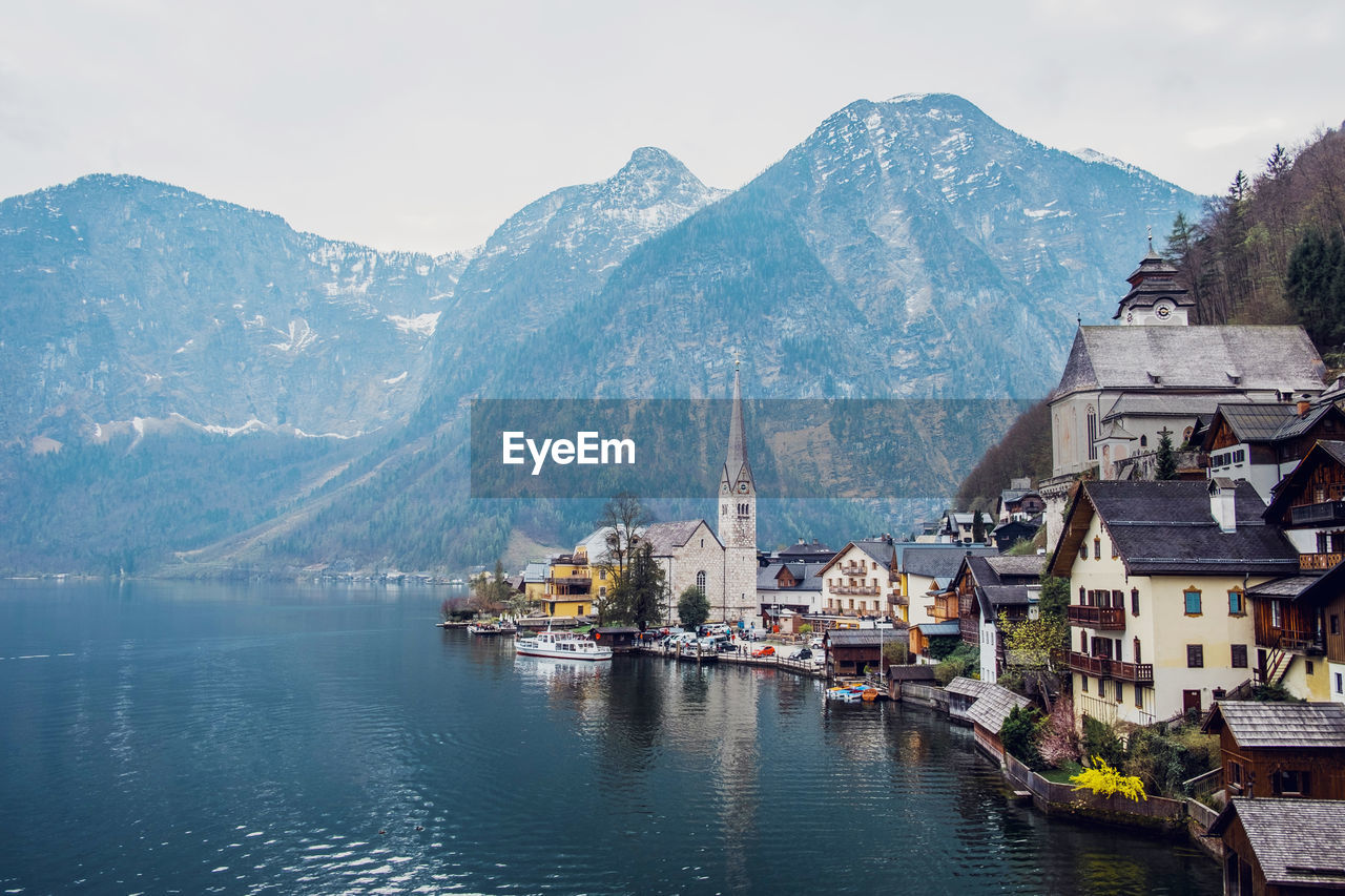 Picturesque landscape of traditional residential houses and famous lutheran parish church of hallstatt located on lake shore surrounded by mountains in austria