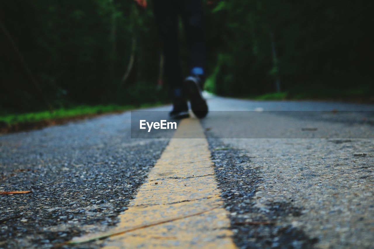 Low section of man walking on road