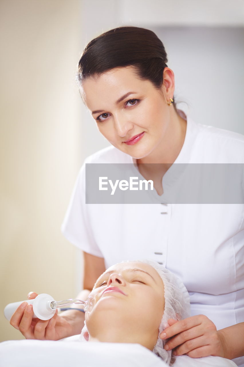 Portrait of beautician giving beauty treatment to woman