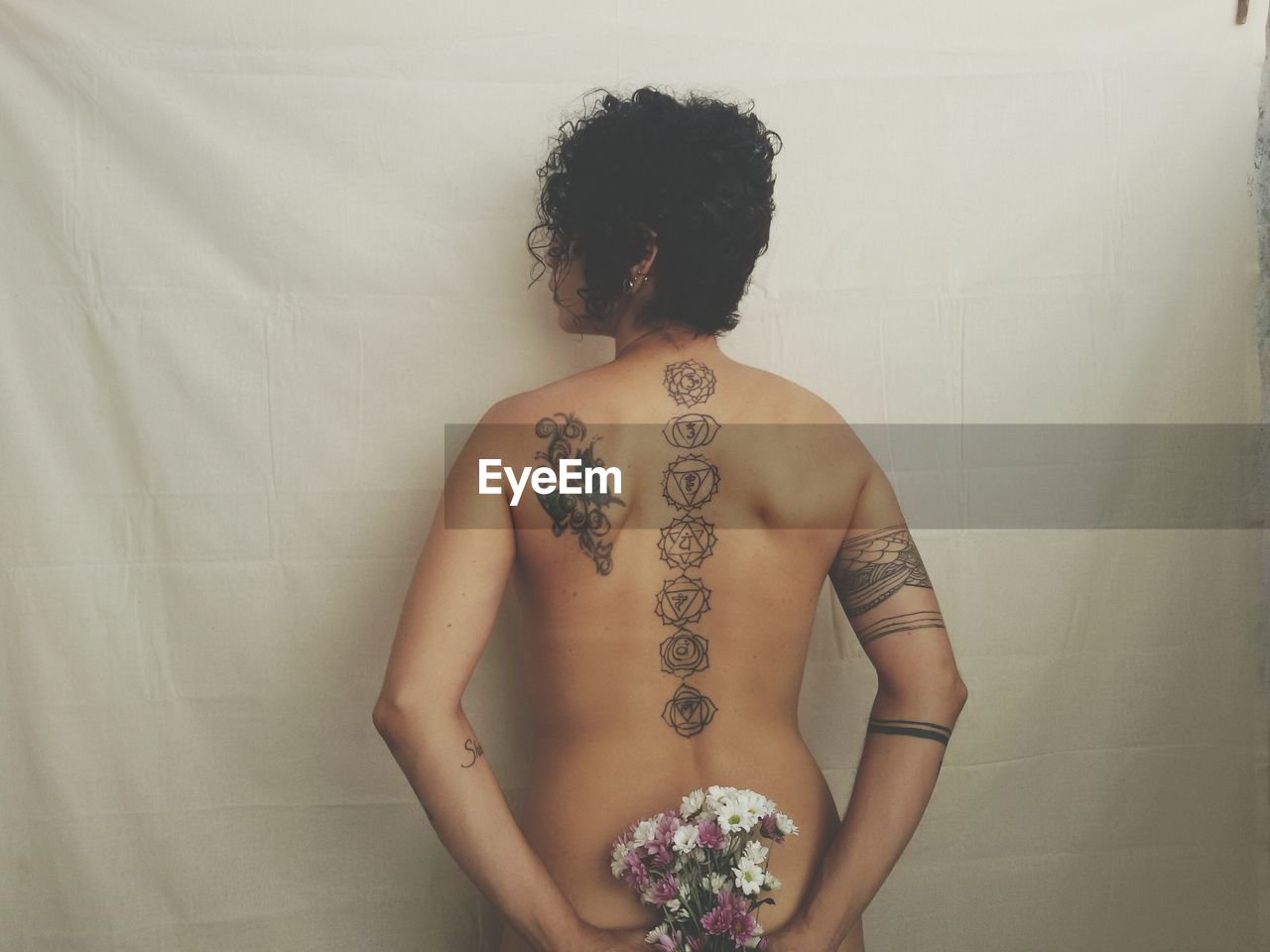 Rear view of shirtless young woman with tattoo on back