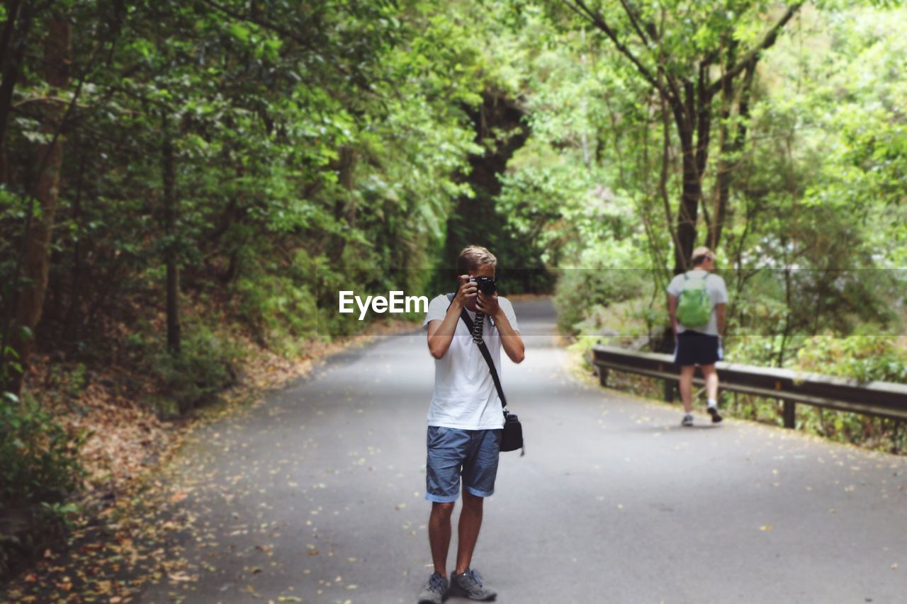 REAR VIEW OF PEOPLE WALKING ON ROAD