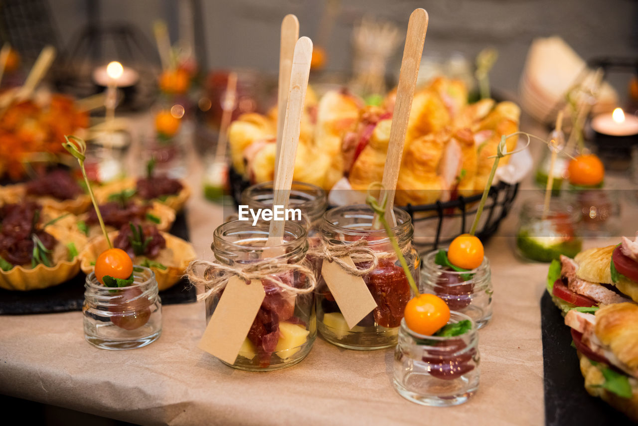 Catering in jars with wooden forks. cold snacks, croissant sandwiches, tartlets, canapés in jars