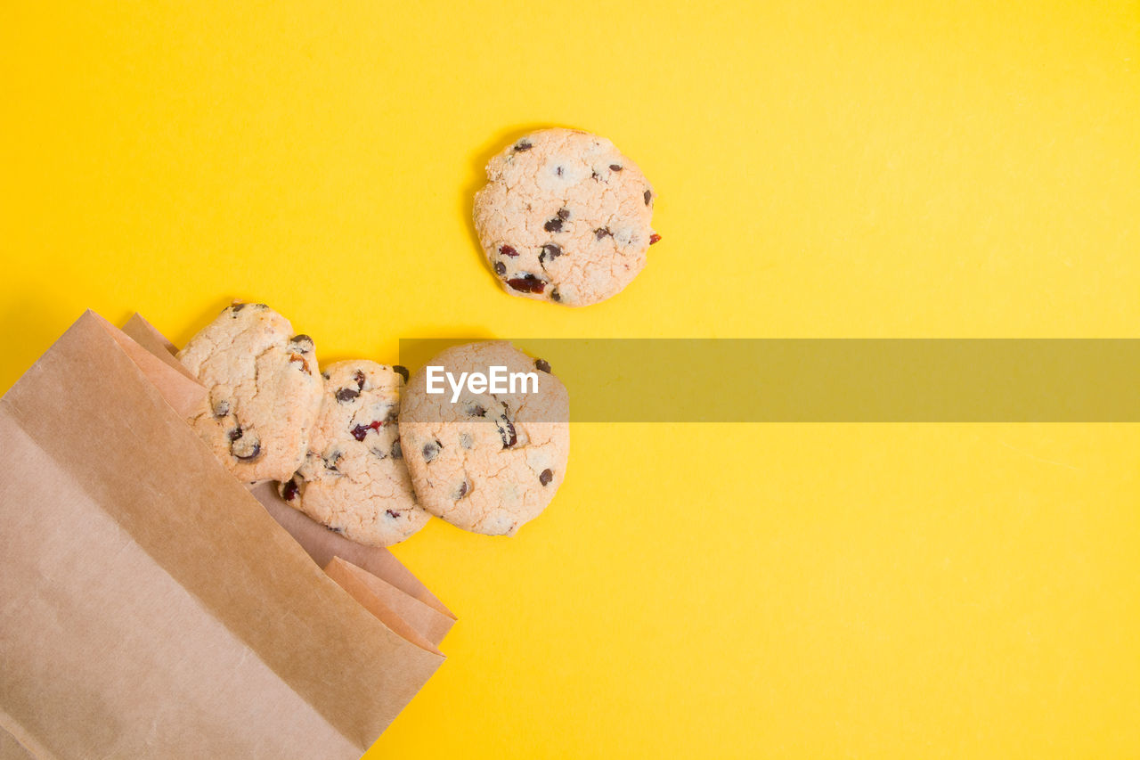 Cookies on a yellow background, cookie chip with pieces of chocolate in a paper bag