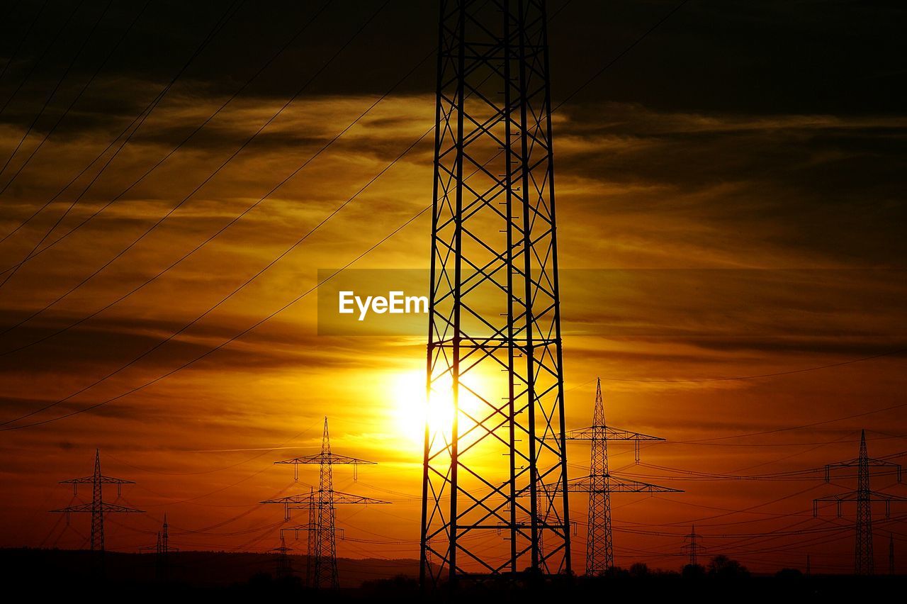 LOW ANGLE VIEW OF SILHOUETTE ELECTRICITY PYLON AGAINST ORANGE SKY