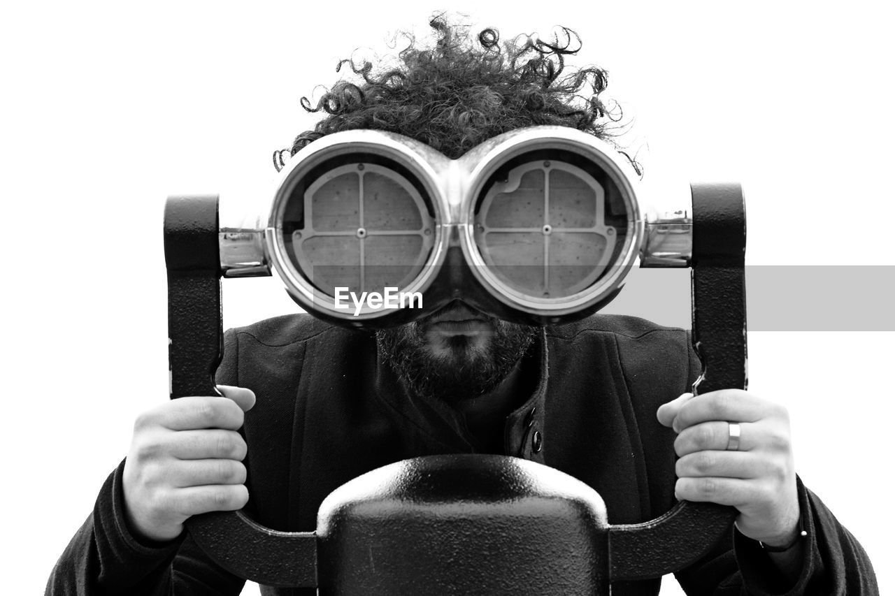 Portrait of man looking through coin-operated binoculars against clear sky