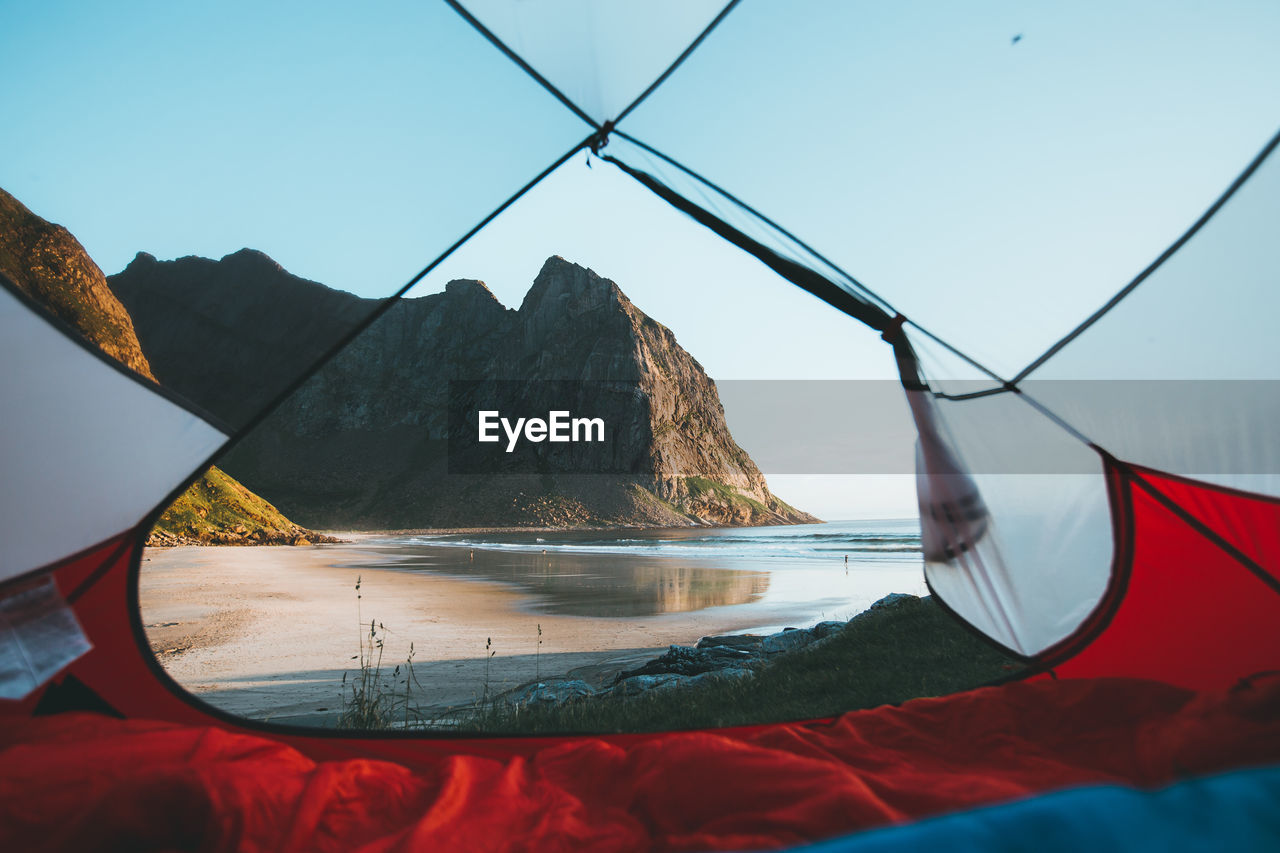 Sea seen through tent against rocky mountains