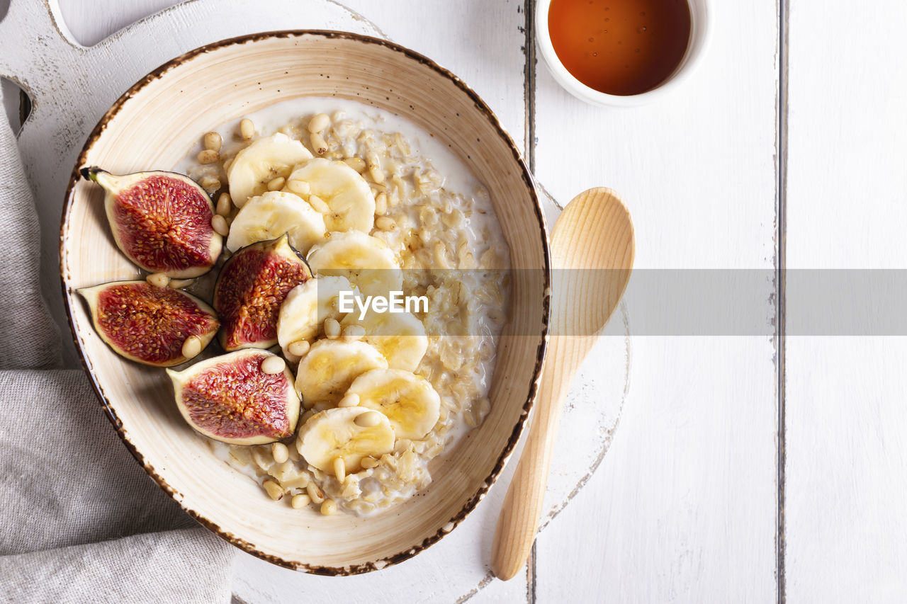 Close up of bowl with oatmeal porridge with figs and bananas for breakfast