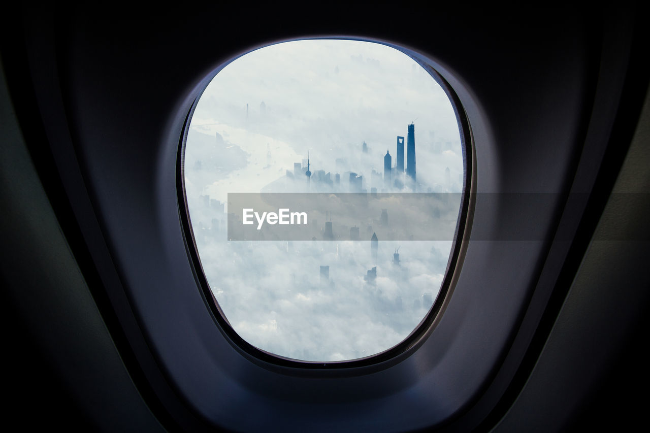 Modern buildings covered with clouds seen through airplane window