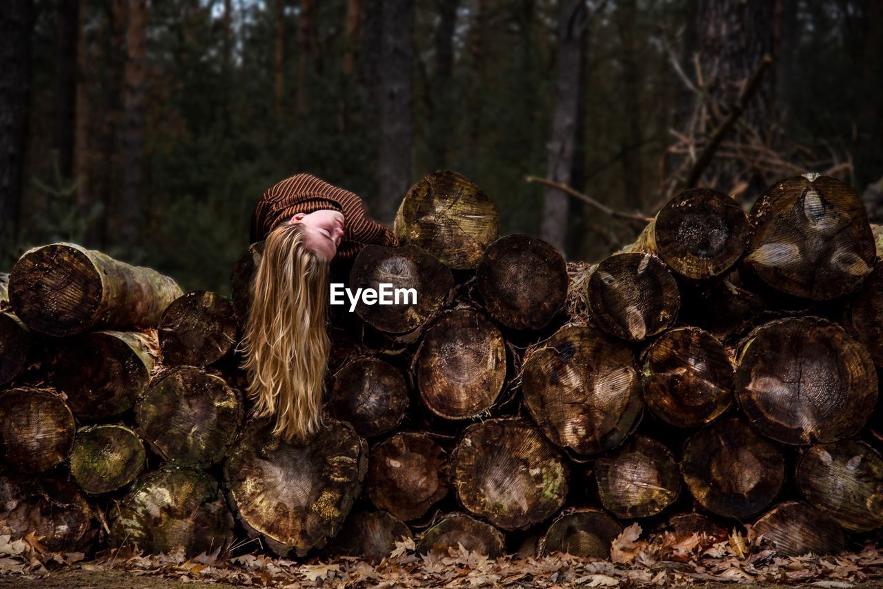 Young woman lying on wooden logs in forest