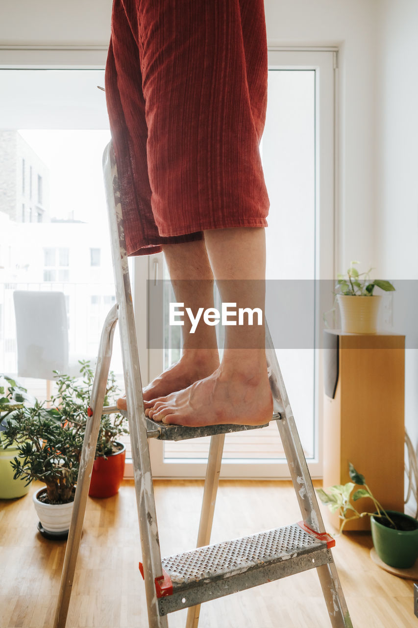 LOW SECTION OF WOMAN STANDING AT HOME