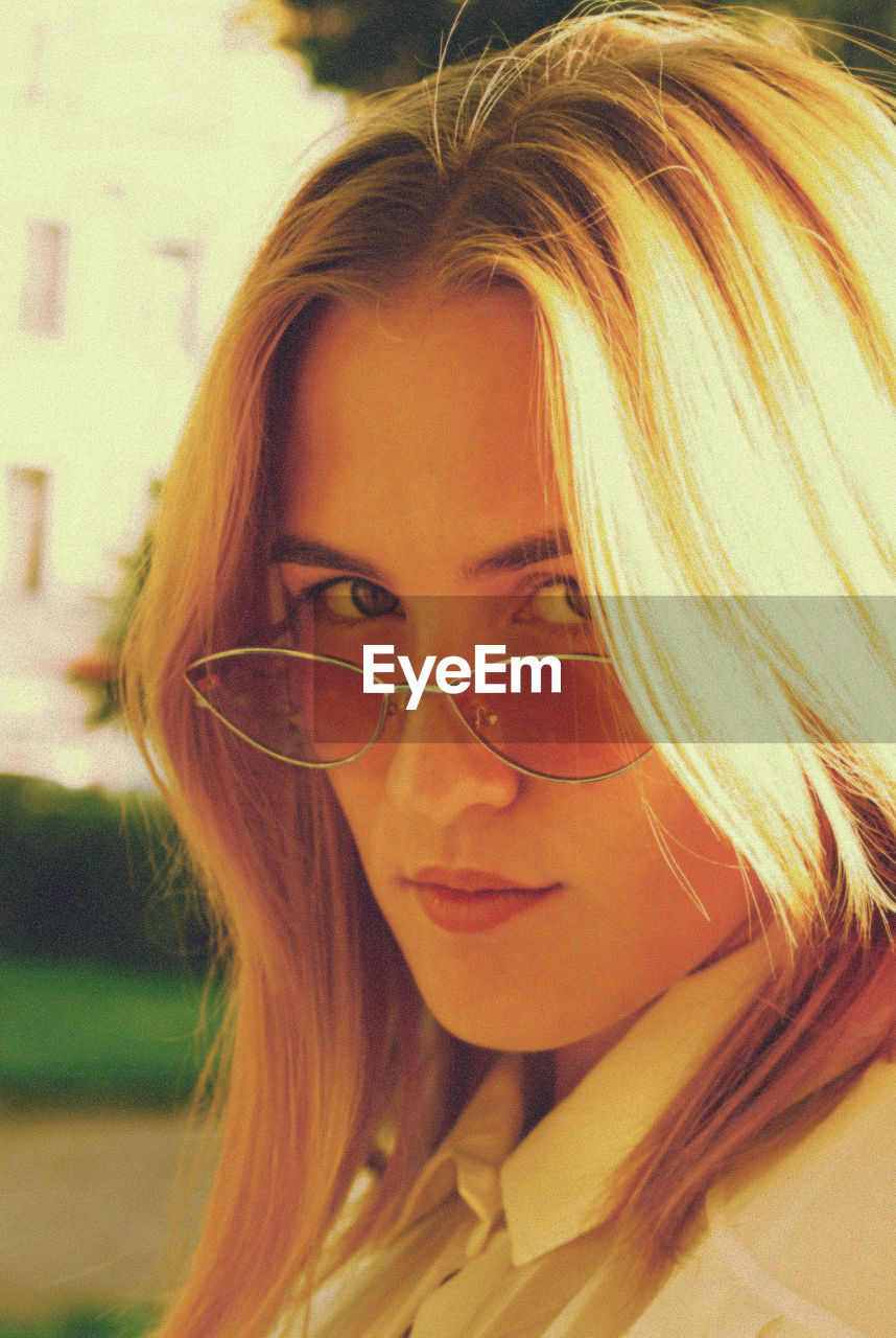 Close-up portrait of young woman wearing sunglasses standing outdoors