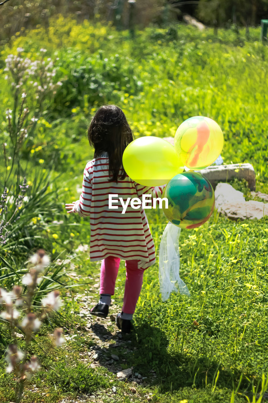 REAR VIEW OF TWO PEOPLE WITH BALLOONS