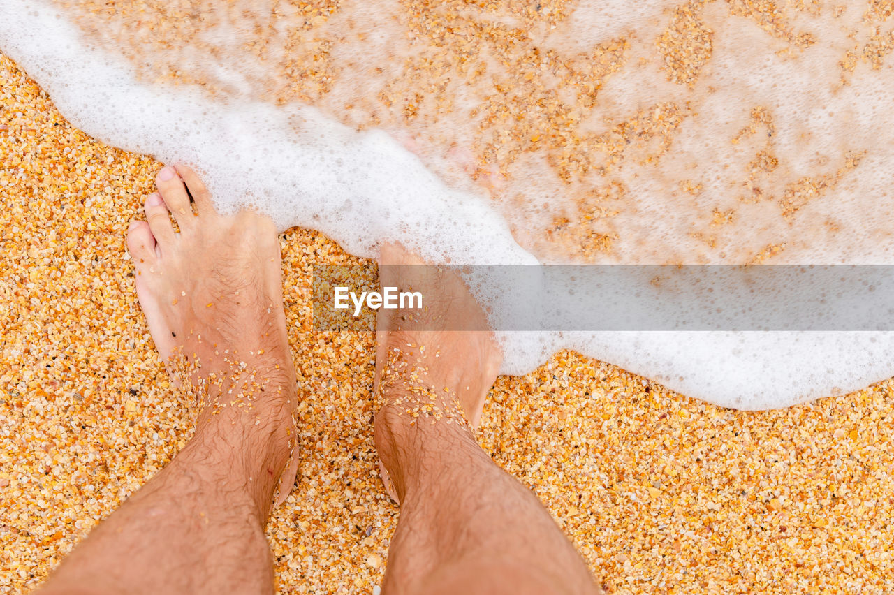 Top view of bare feet in the sand on the beach. foaming sea texture of ocean and sand, standing