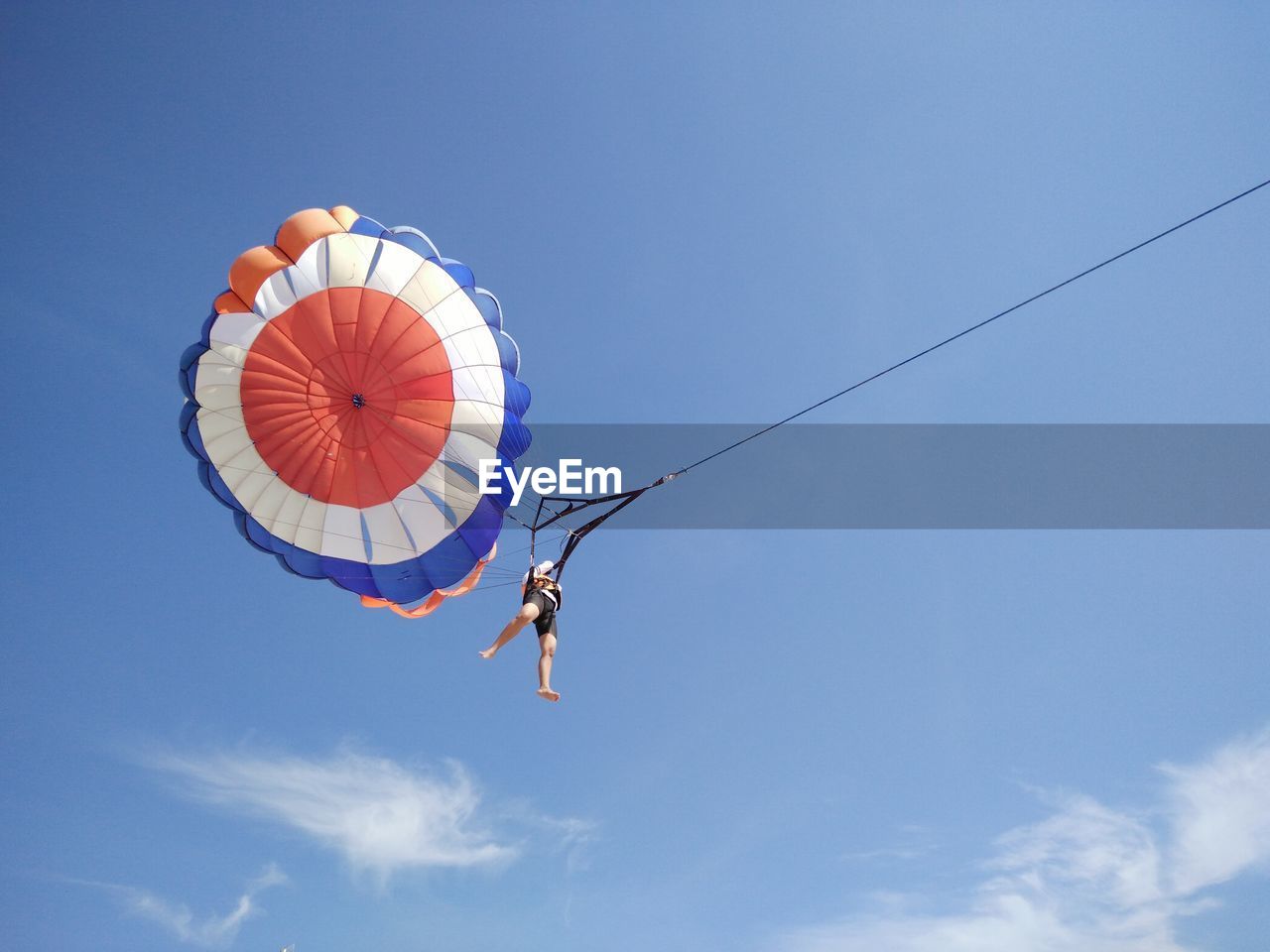 Low angle view of person parasailing against blue sky