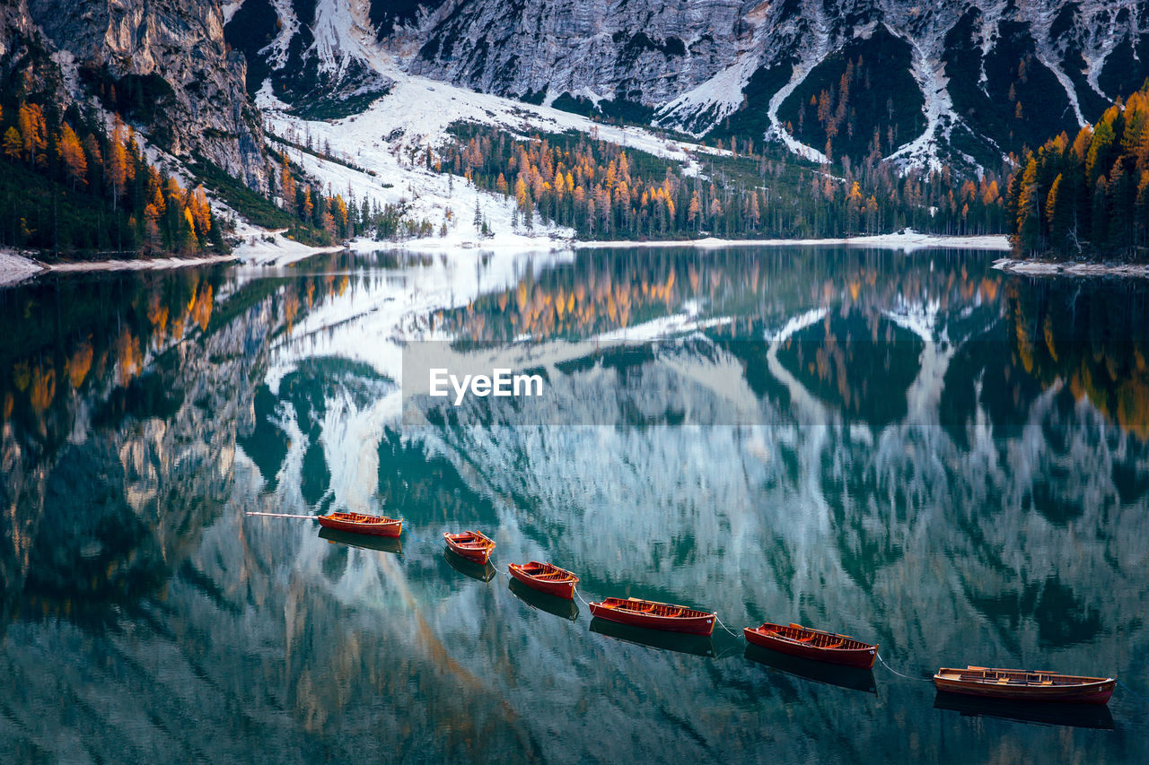 Boats in lake against snowcapped mountains