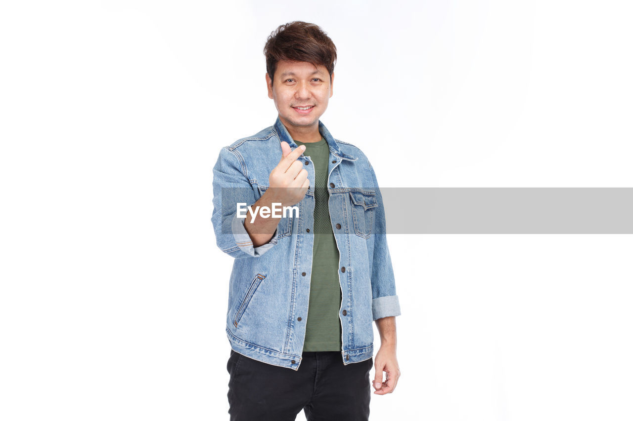 PORTRAIT OF A SMILING YOUNG MAN AGAINST WHITE BACKGROUND