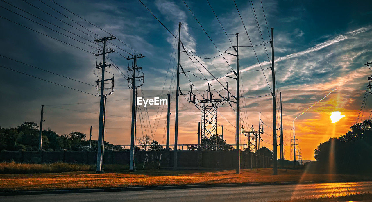 low angle view of electricity pylons against sky during sunset