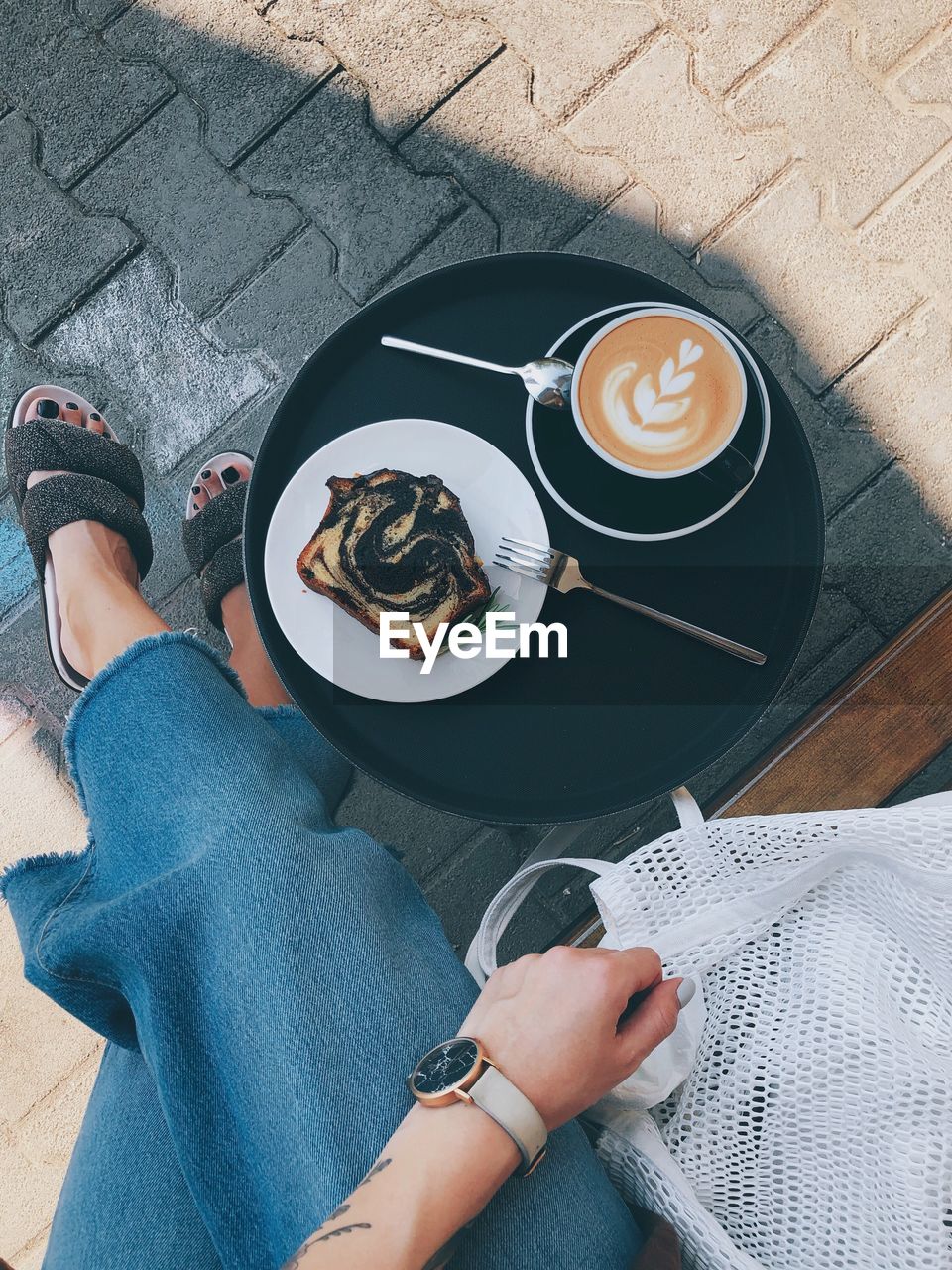 Low section of woman with coffee cup and dessert