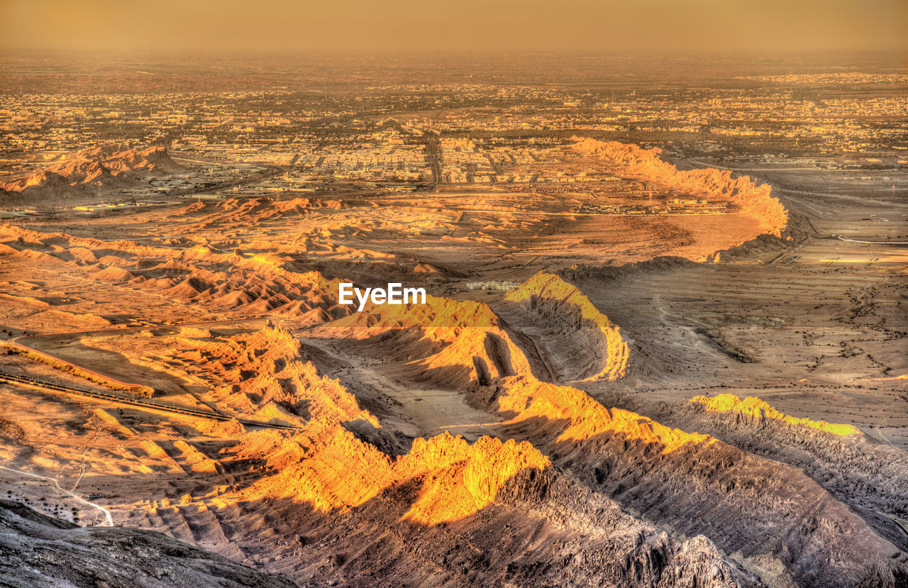 HIGH ANGLE VIEW OF ILLUMINATED CITY DURING SUNSET