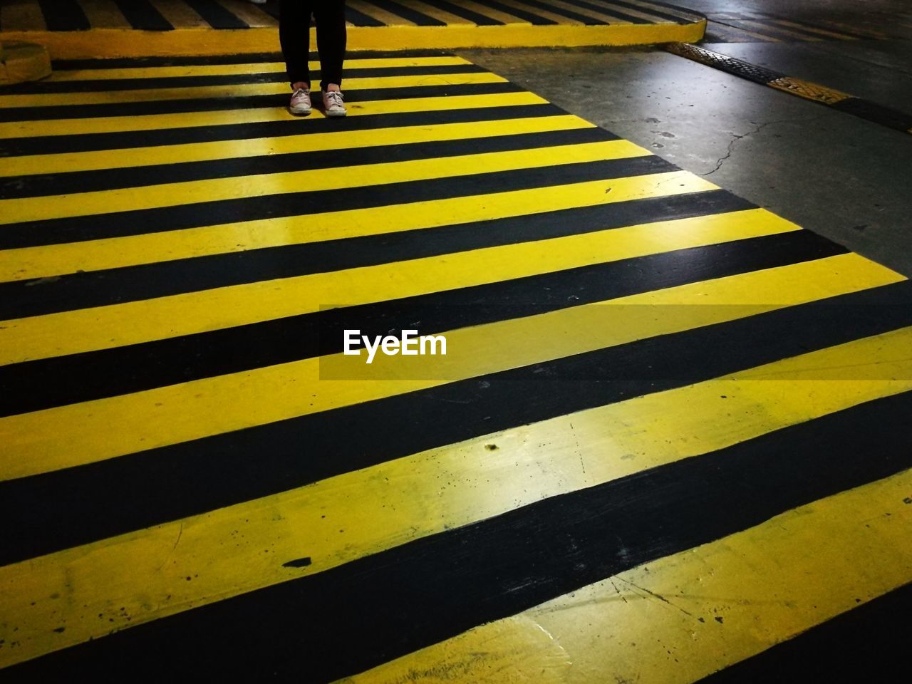 Low section of person walking on zebra crossing