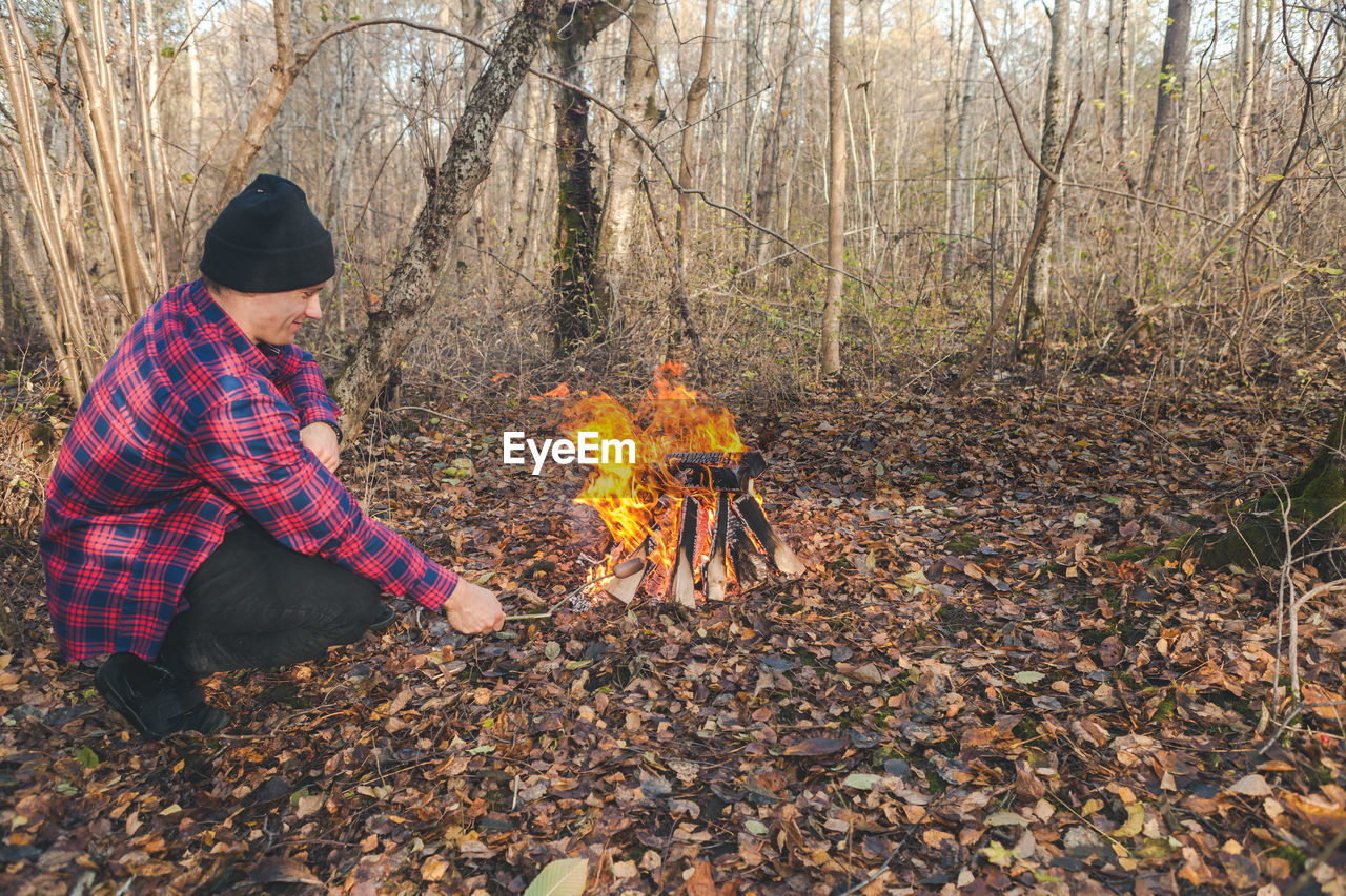 Man roasting food in campfire at forest
