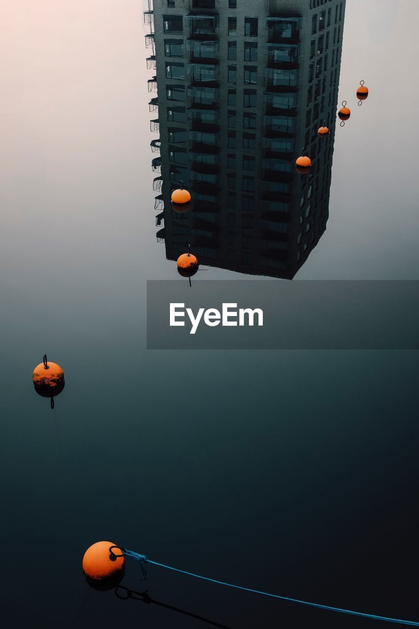 High angle view of buoys on calm lake with building reflection