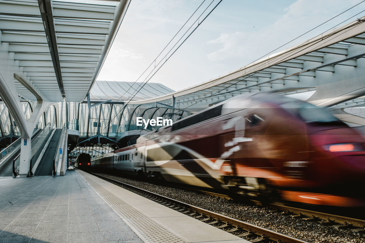 Blurred motion of train at railroad station platform against sky