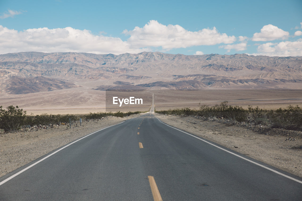 Road by desert against sky