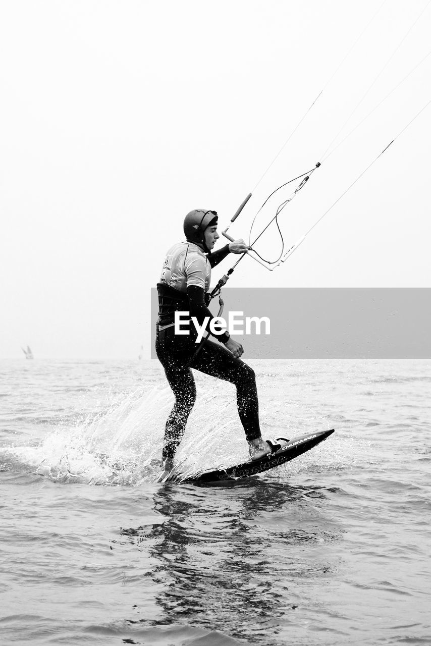 Man wakeboarding on sea against clear sky