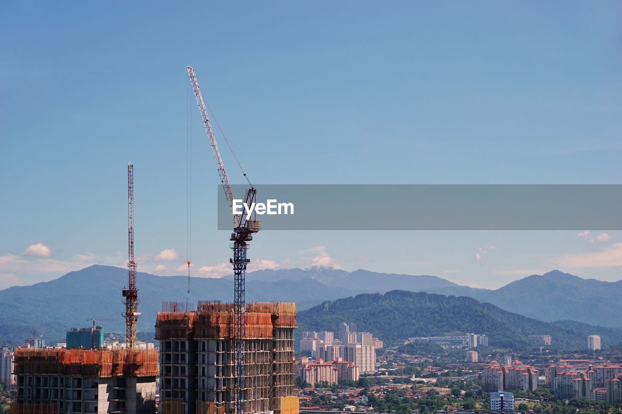 Cranes in city against clear sky