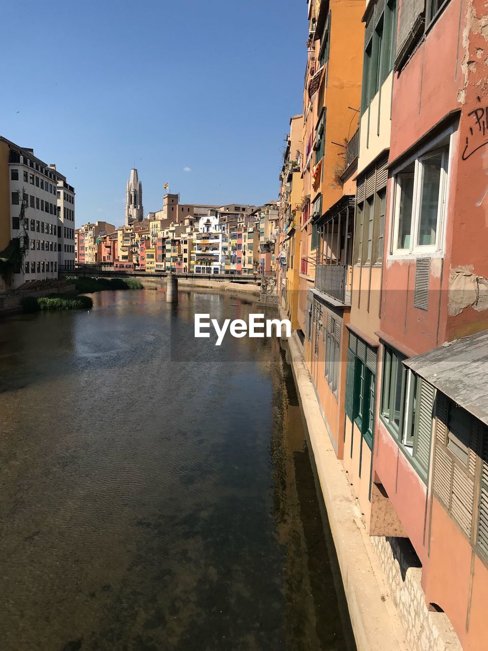 Canal amidst buildings against clear sky