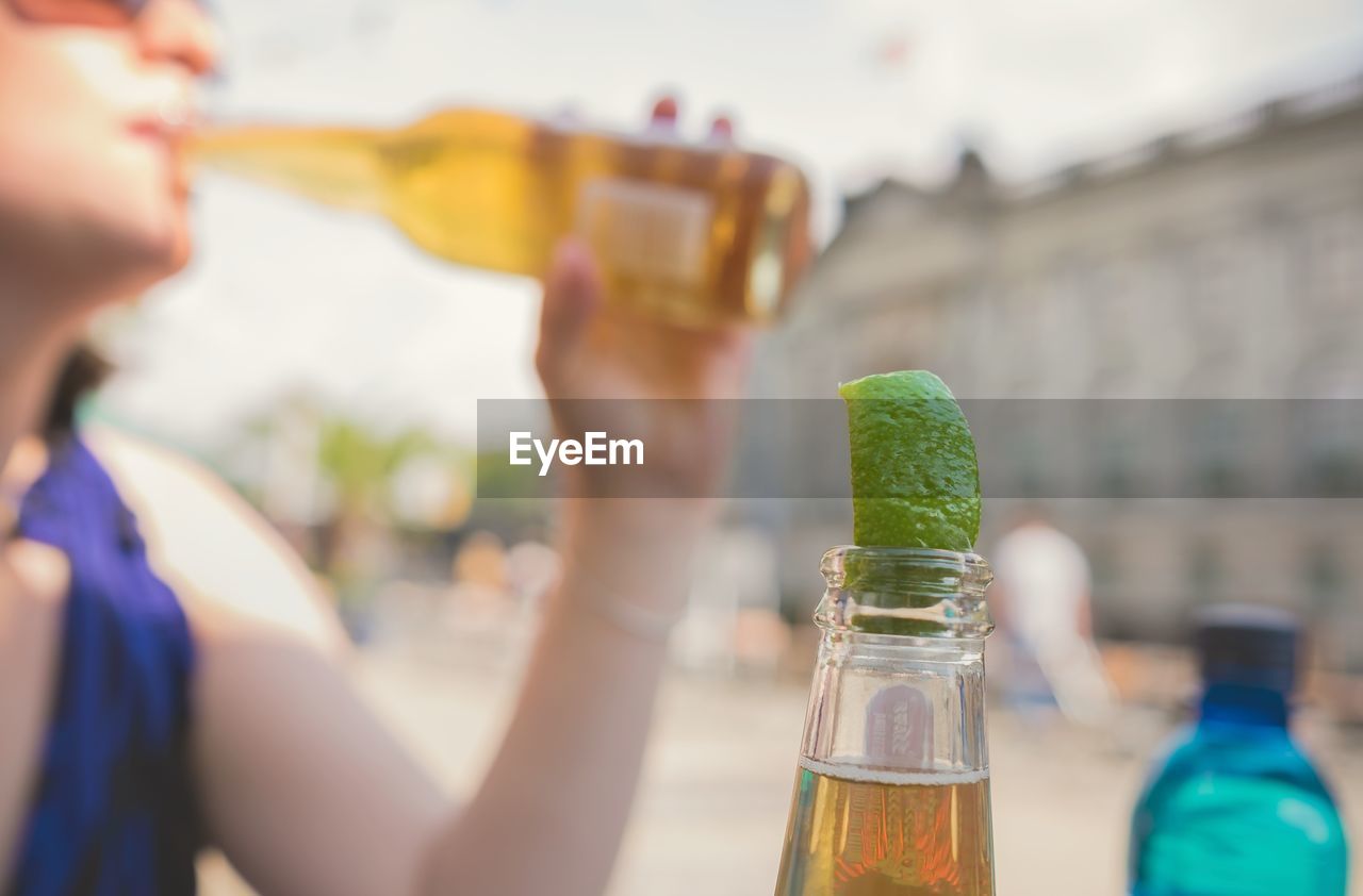Cropped image of woman drinking beer on street