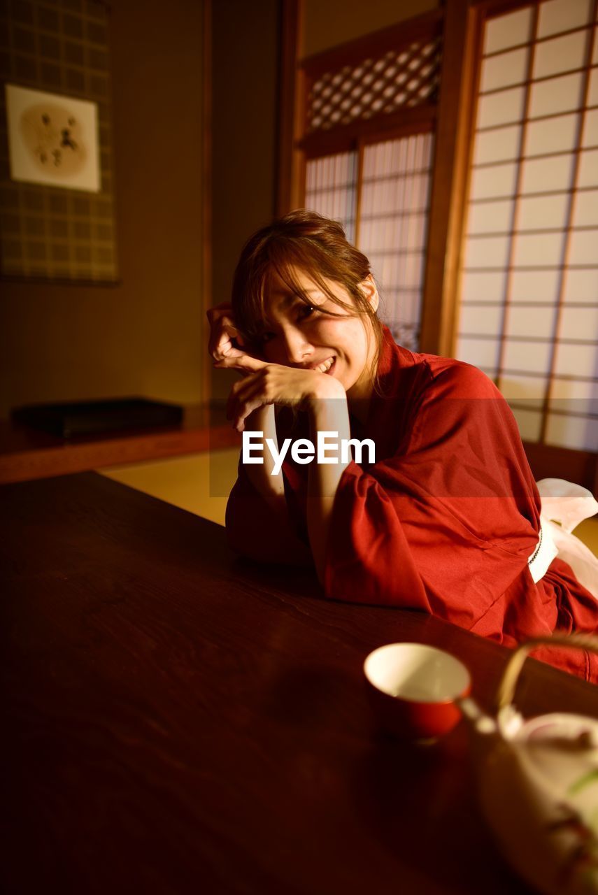 Young woman sitting on table at home