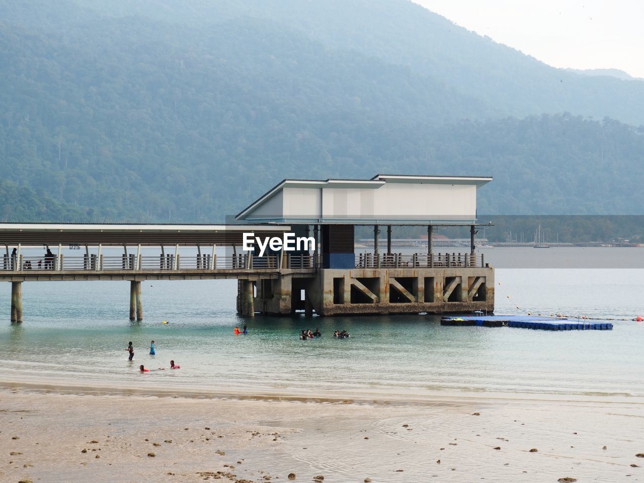 BUILT STRUCTURE ON BEACH AGAINST MOUNTAIN