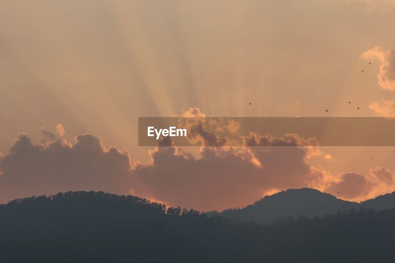 View of silhouetted mountains against cloudy sky at dawn