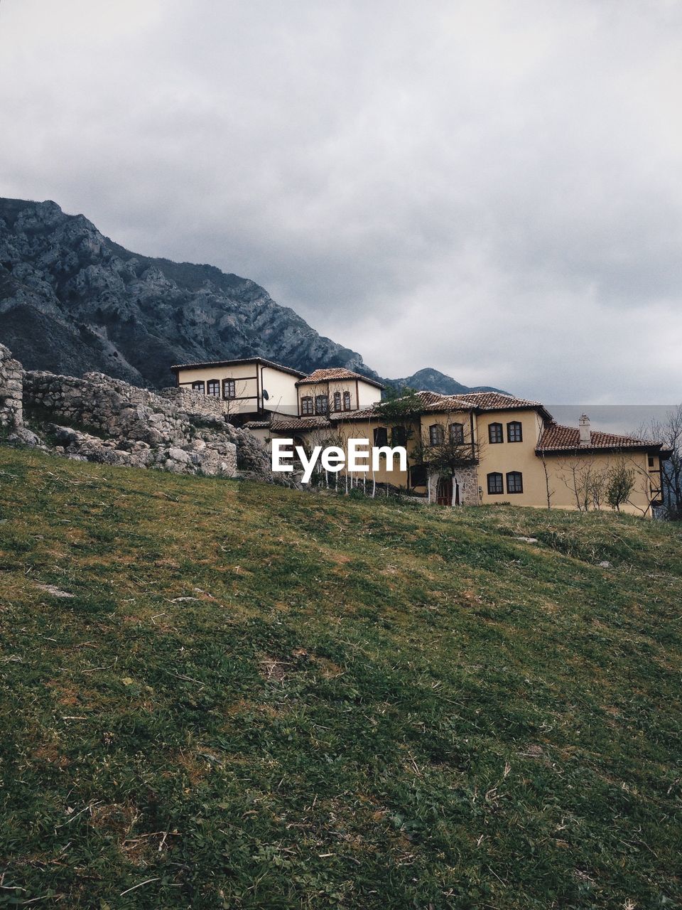 View of houses on hill against cloudy sky