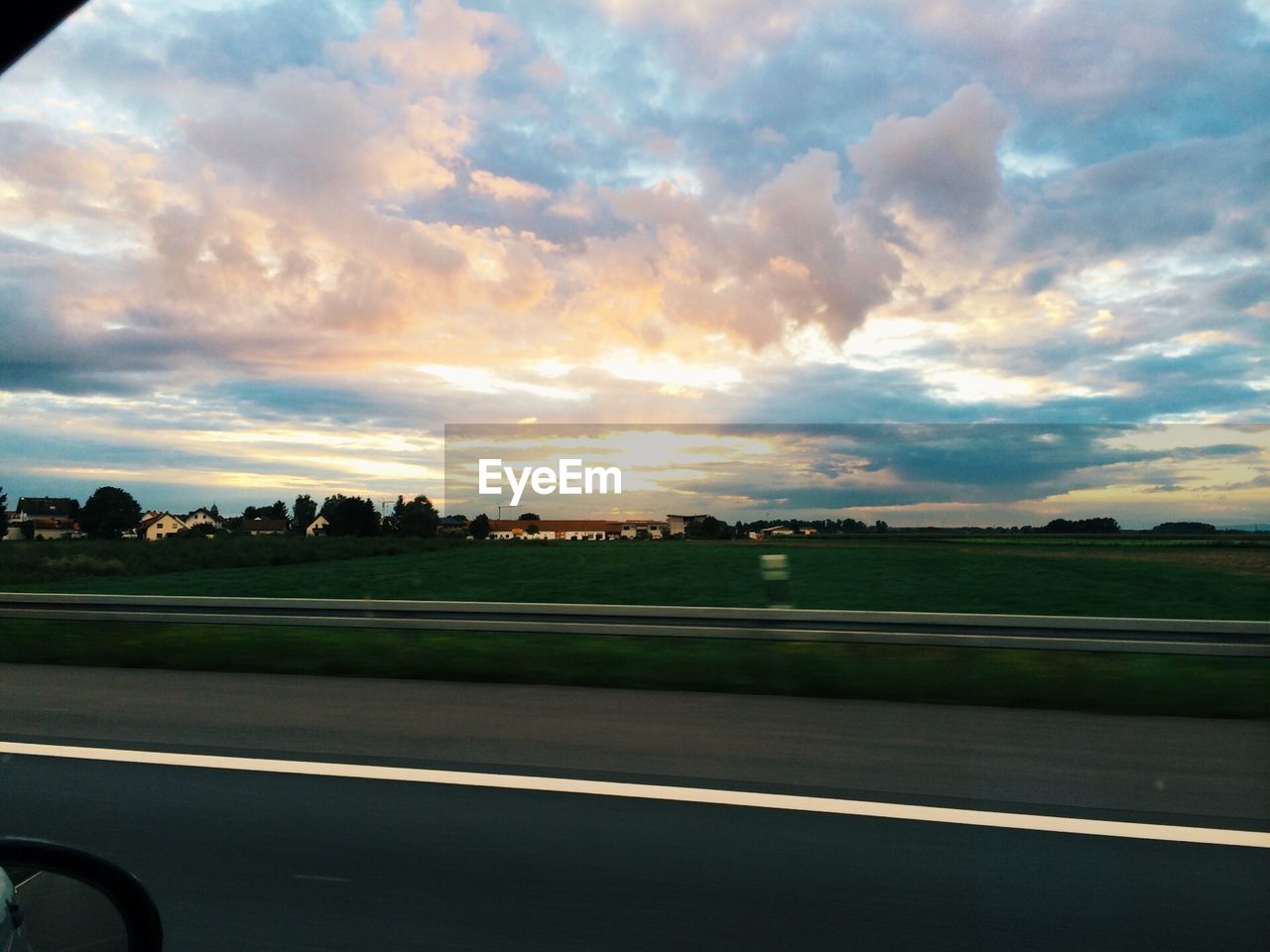 Scenic view of field at sunset through car window on country road