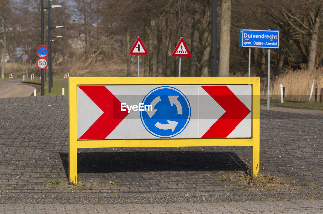 Information sign on road against wall